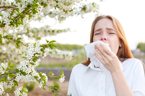 Young woman covering sneeze outdoors