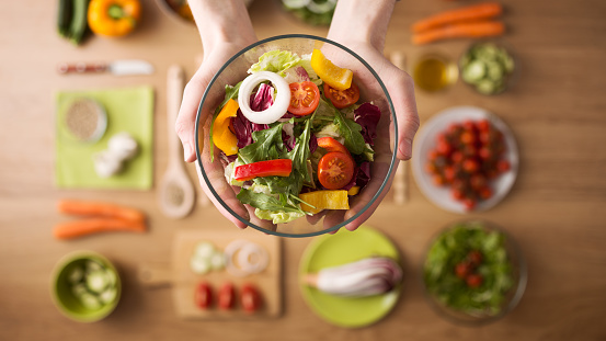 Hands holding salad bowl over ingredients