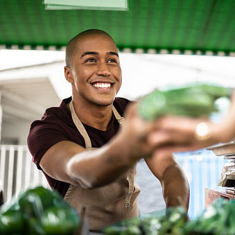 Young man handing a vegetable to a customer