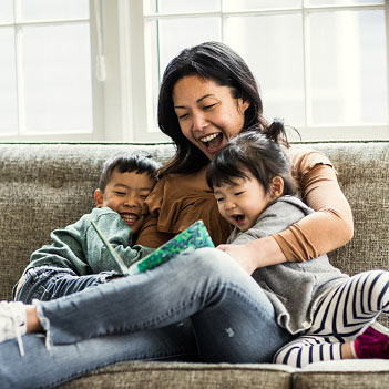 Mother reading with her children on couch