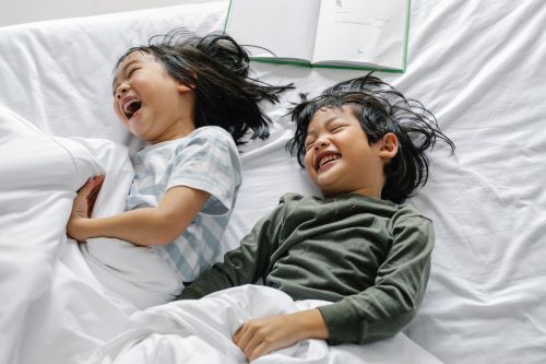 two children in bed under sheets